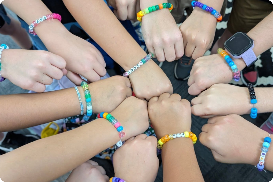 kids putting their fists in a circle showing off beaded bracelets
